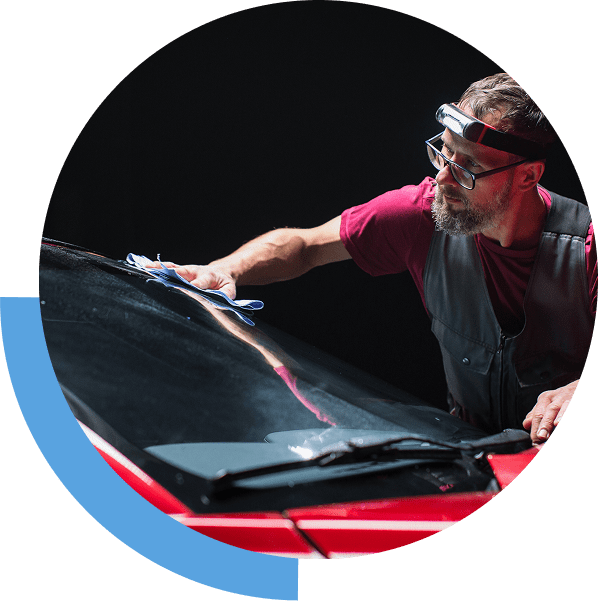 Man painting a car hood in a dimly lit workshop.