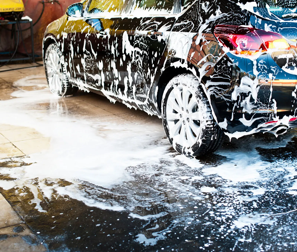 Black car covered in soap foam during a wash.